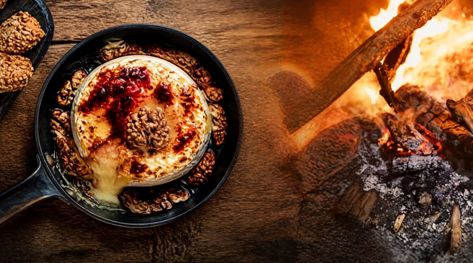 Charcuterie board and cast iron skillet of baked Brie set out at a fall campsite
